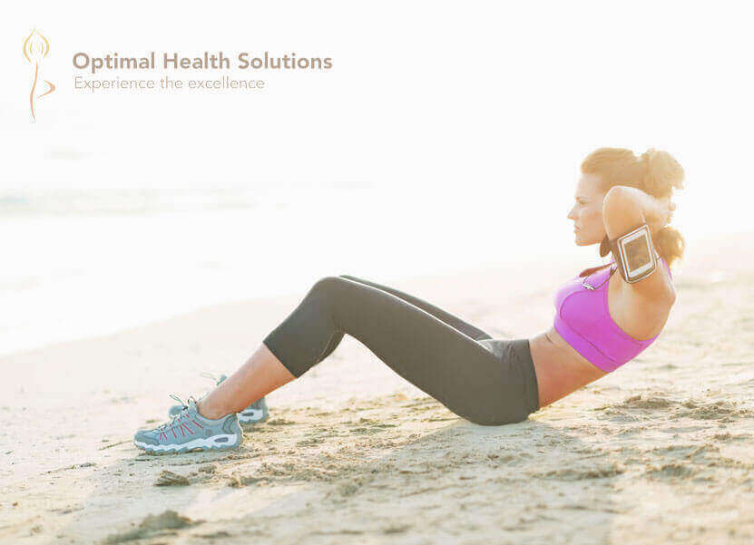 Fitness young woman doing abdominal crunch on beach